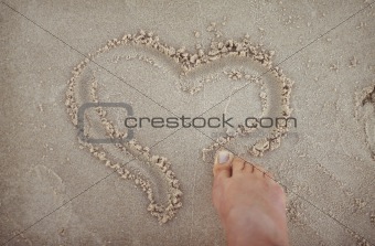 Drawing a heart shape in the sand.