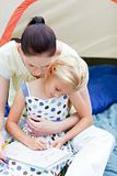 Mother and daughter wirting in tent