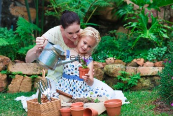 Young mother and daughter watering plants
