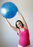 Young smiling pregnant woman exercising with fitness ball.