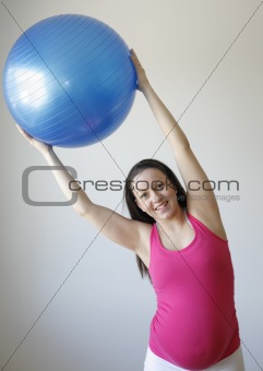 Young smiling pregnant woman exercising with fitness ball.