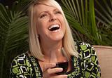 Beautiful blonde smiling woman at an evening social gathering tasting wine.