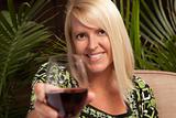 Beautiful blonde smiling woman at an evening social gathering tasting wine.