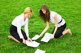 Two business women gather around on the grass paper
