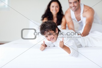 Happy family on bed with thumbs up