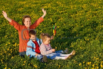 Woman with kids on the spring field full of dandelions