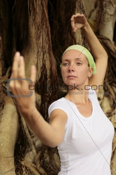 Woman in white meditating in front of Bodhi Tree Roots