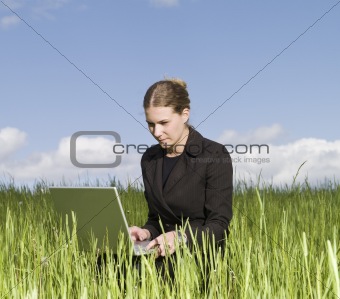 Woman with a computer in the grass