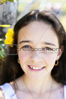 Close-up portrait of a pretty, dark haired young girl outdoors.
