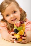 Little girl holding a summer fruits salad with bubbles