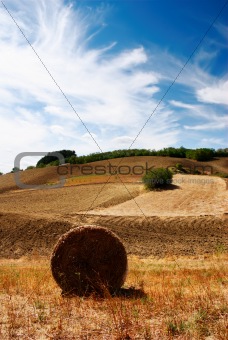 Hay bale in a golden dry field with interesting blue sky