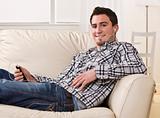 Attractive brunette male sitting on couch.