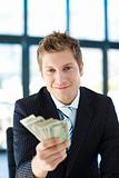 Junior businessman holding dollars and looking to the camera