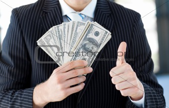 Businessman showing dollars with thumbs up
