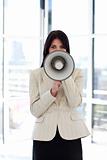 Brunette businesswoman shouting through megaphone