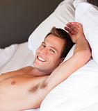 Smiling young man relaxing in bed