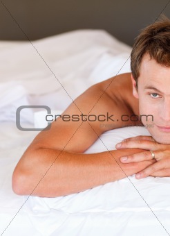 Young man relaxing in bed looking at the camera