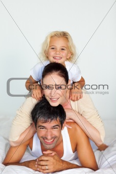Father, mother and daughter playing in bed 