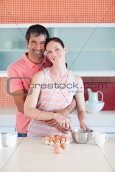 Happy couple cooking together looking to the camera