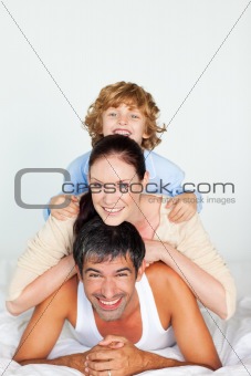 Father, mother and son playing in bed 