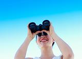 Smiling businesswoman looking through binoculars
