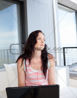 Thoughtful woman using her laptop