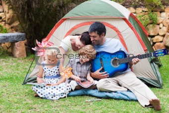 Parents and children playing a guitar in a tent