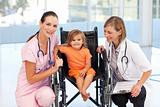 Little girl in a wheelchair with nurse and doctor