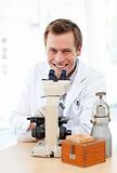 Smiling scientist looking through a microscope