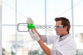 Serious scientist examining a chemical test-tube with copy-space