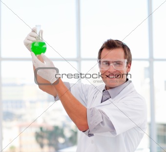 Scientist examining a test-tube smiling at the camera