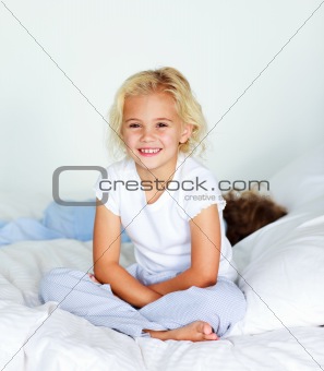 Little girl sitting on bed smiling at the camera