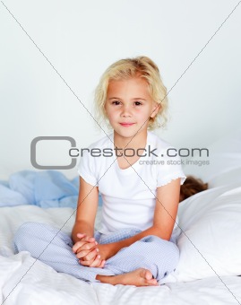 Little girl sitting on bed looking at the camera