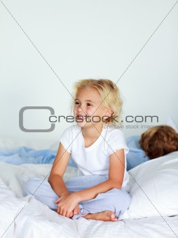 Smiling blonde girl sitting on a bed