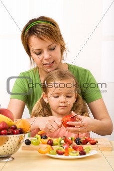 Woman and little girl slicing fruits