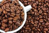 White cup with coffee beans on background
