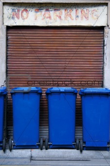 Blue garbage bins parked in a no parking zone