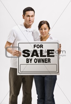 Worried Couple Holding For Sale Sign