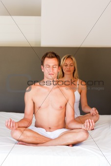 Couple doing exercises on bed with copy-space