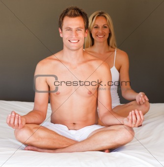 Smiling couple doing exercises on bed