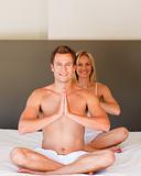 Young couple doing yoga moves on bed