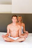 Young couple doing yoga on bed