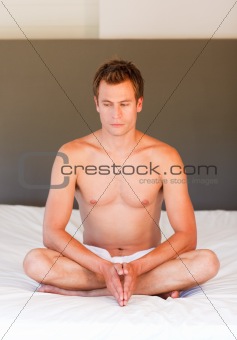 Young boy doing yoga moves on bed