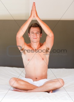 Young boy doing buddha exercises on bed