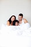 Family playing with his son in bed with copy-space