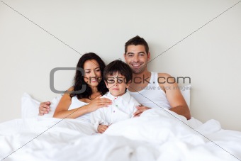 Couple and son sitting in bed