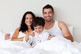 Portrait of a son with thumbs up and his parents in bed