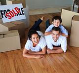 Family moving house on floor smiling at the camera