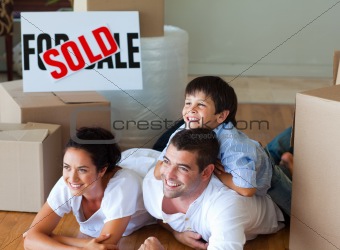 Happy family moving house lying on floor