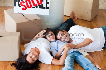 Smiling family in their new house lying on floor